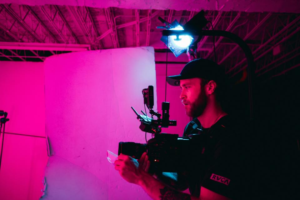 Cameraman filming a scene with pink lighting